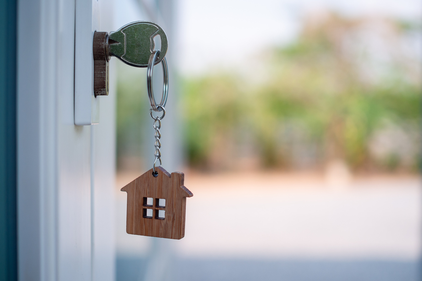 Close-up of Key in a Door with House Keychain